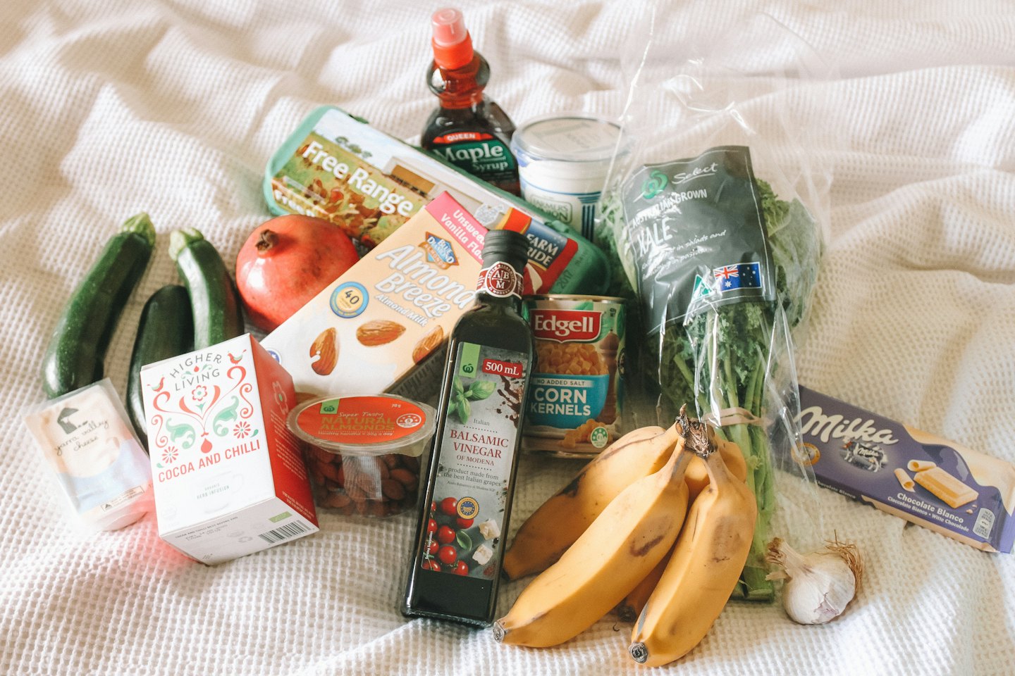 Assorted fresh produce and pantry staples arranged on a white blanket.