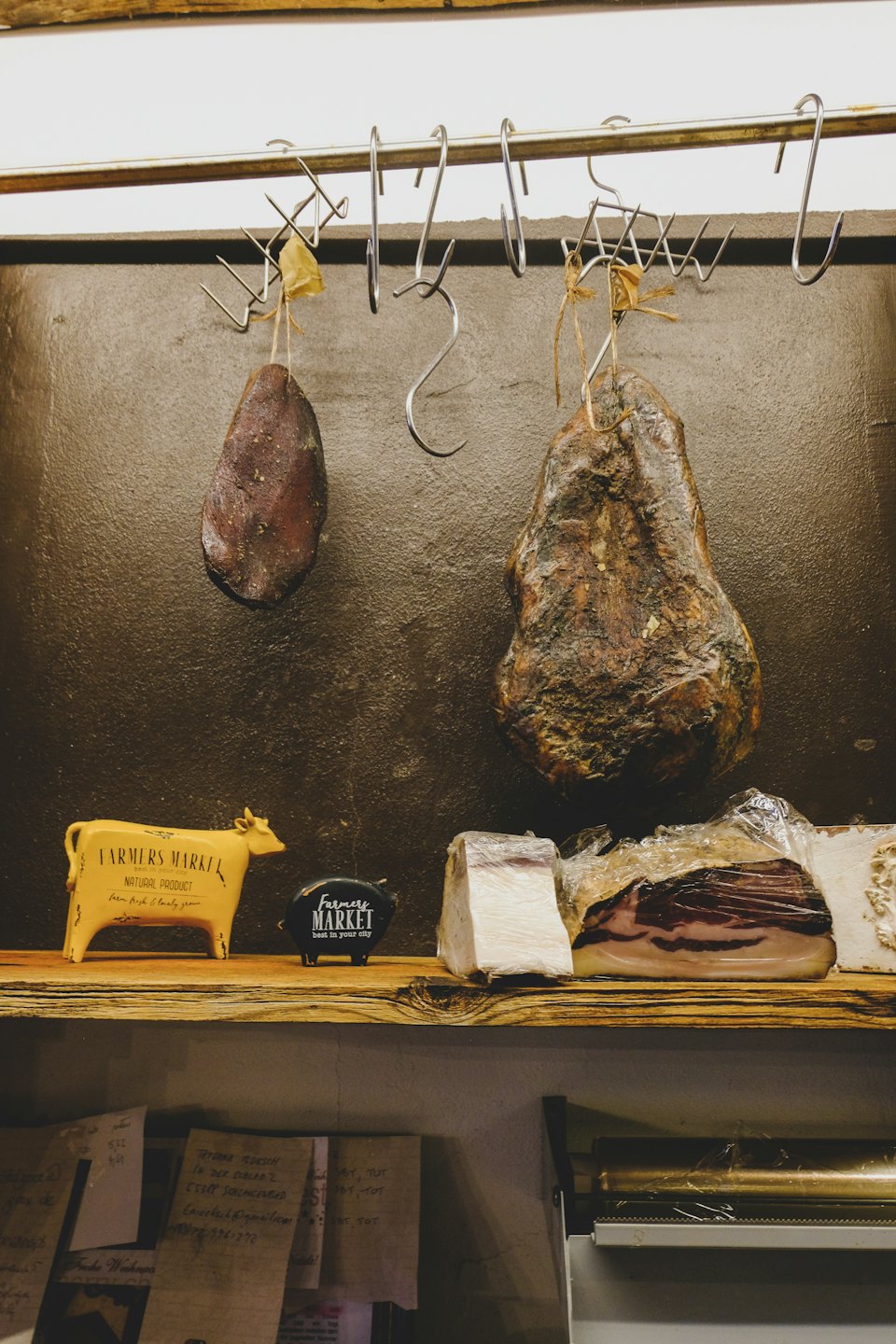 Cured meats hang above a shelf with animal figurines.