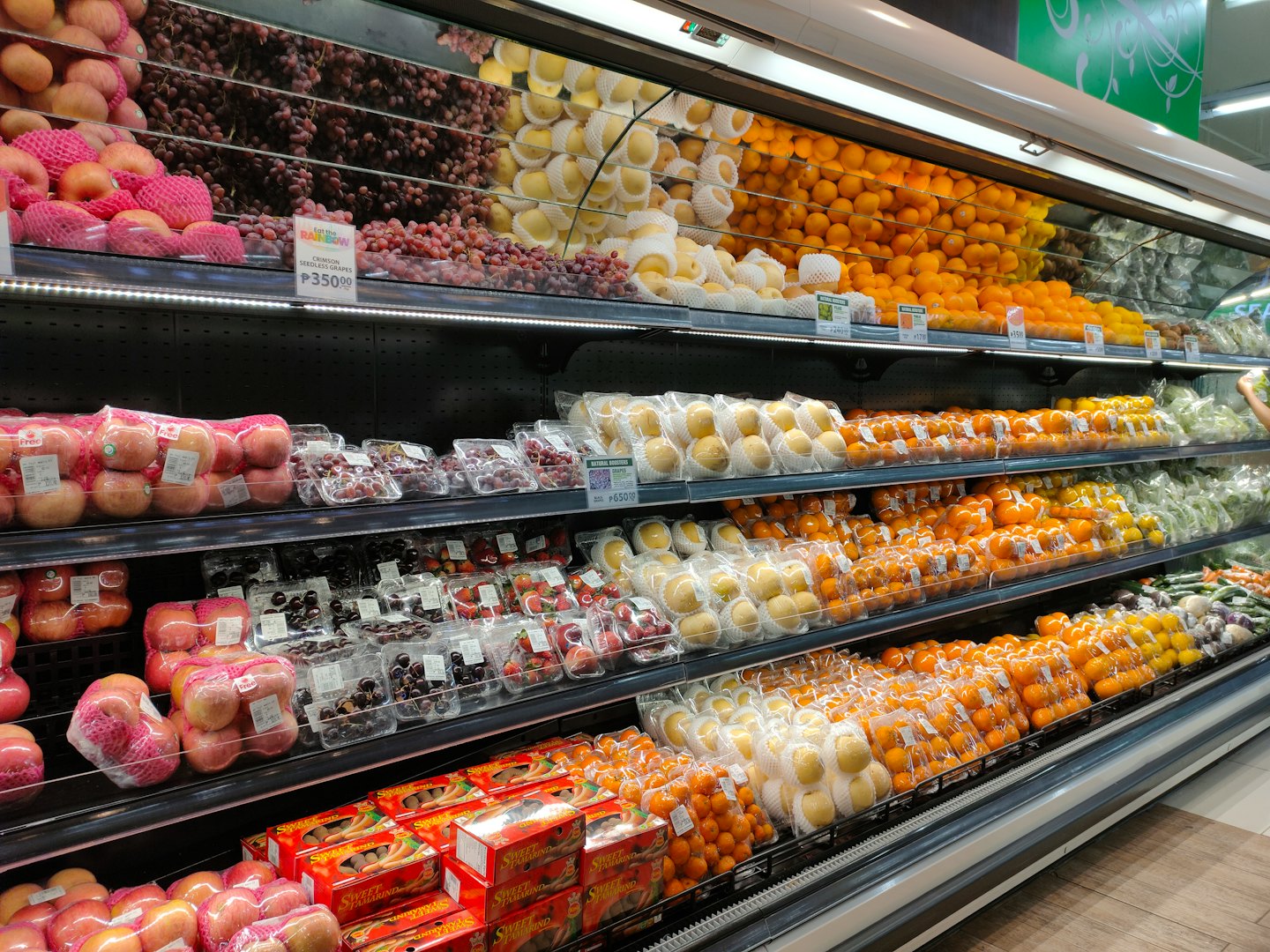 Supermarket produce aisle with neatly arranged fruits and vegetables.