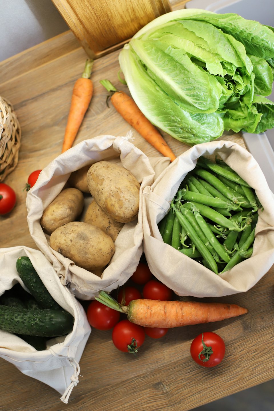 Fresh vegetables are arranged on a wooden kitchen surface.